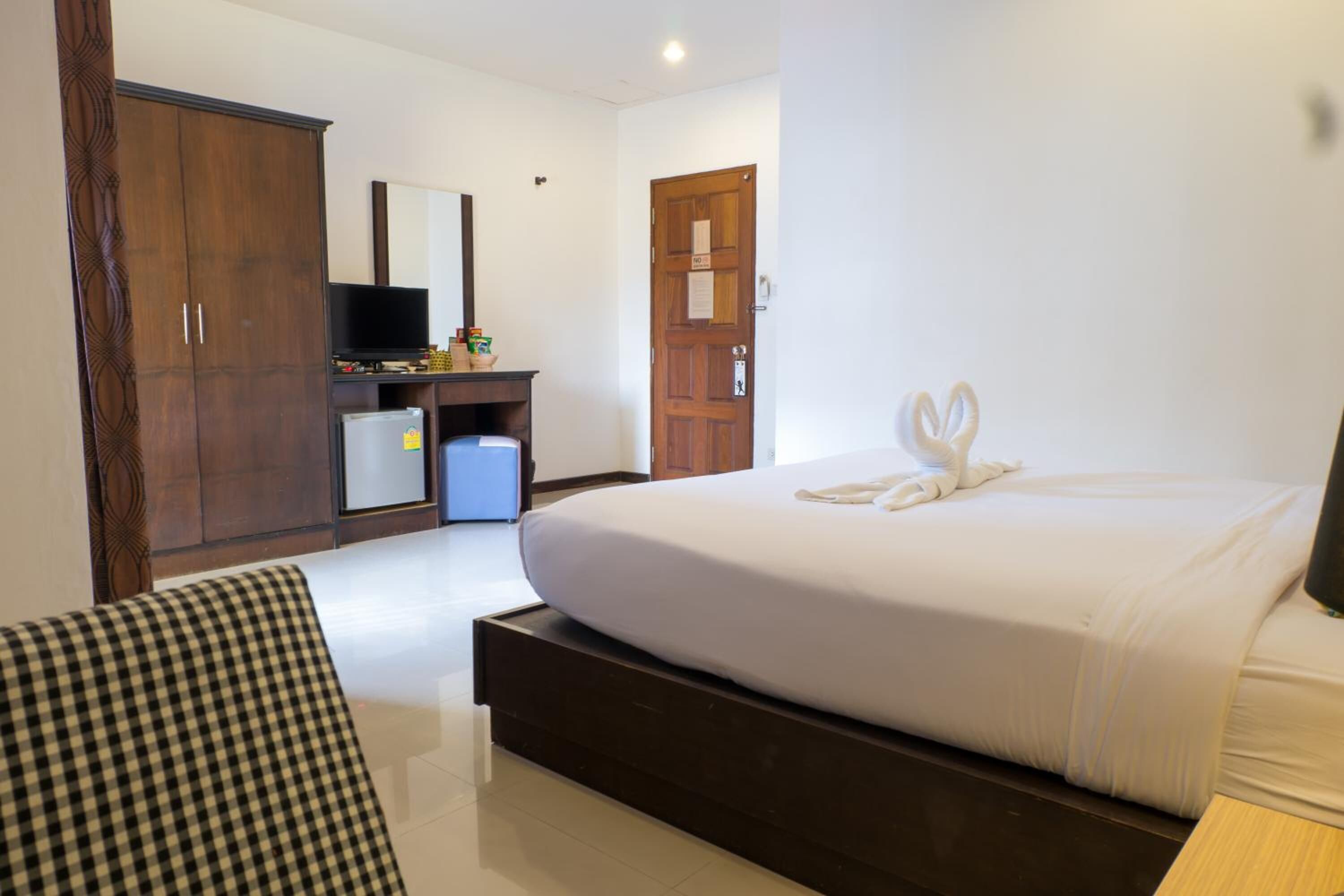 A hotel room with a large bed, a wardrobe, a television, and a desk with a mirror.