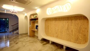 A modern interior with a wooden accent wall, a chandelier, and a staircase. - Nomad Pension in Jeju (Seogwipo)