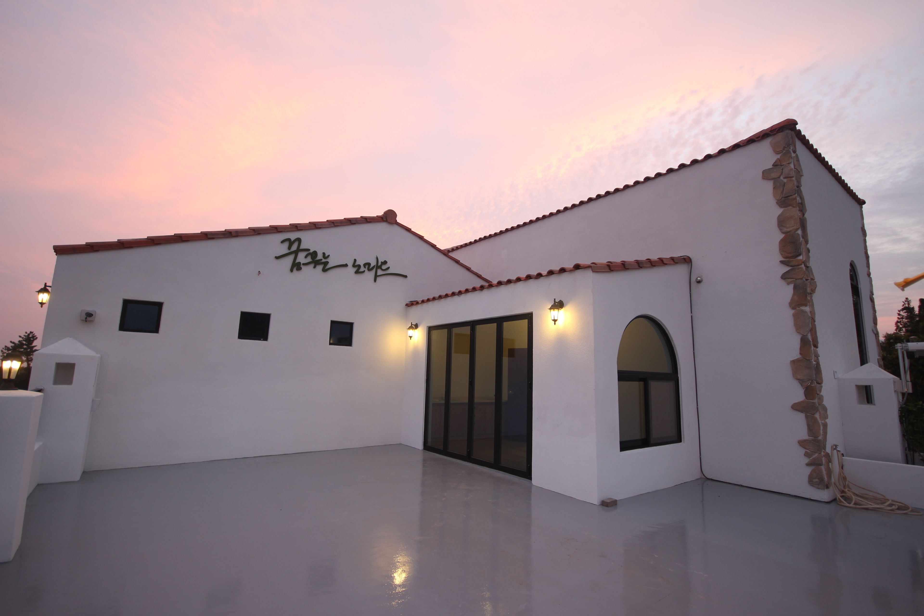 Un edificio blanco con techo de tejas y un muro de piedra decorativo.