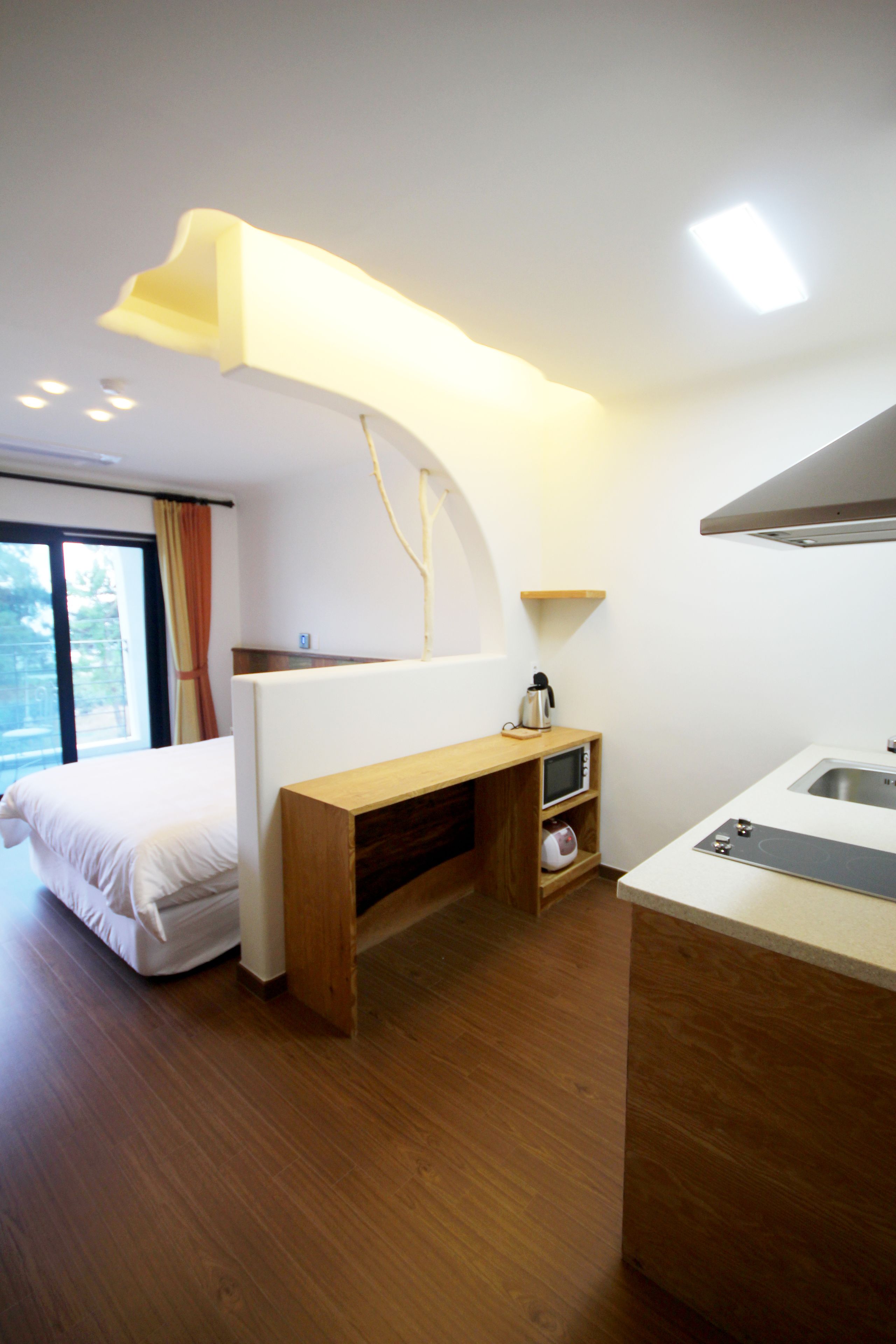Une chambre d’hôtel moderne équipée d’un lit, d’un bureau en bois, d’un four à micro-ondes et d’un lavabo.
