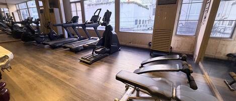 Un gimnasio con cintas de correr, bicicletas estáticas y máquinas de pesas.
