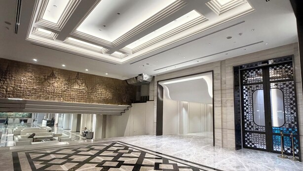 A spacious lobby with a geometric marble floor, a high ceiling with recessed lighting, and a modern entrance. - Grace Hotel (Bangkok)