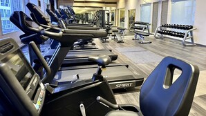 A gym with multiple treadmills, weight benches, and dumbbells. - Grace Hotel (Bangkok)