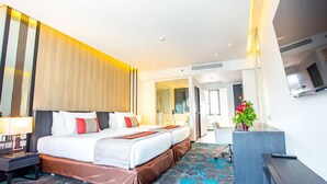 A hotel room with a large bed, a desk, and a bathroom visible through an open door. - Grace Hotel (Bangkok)