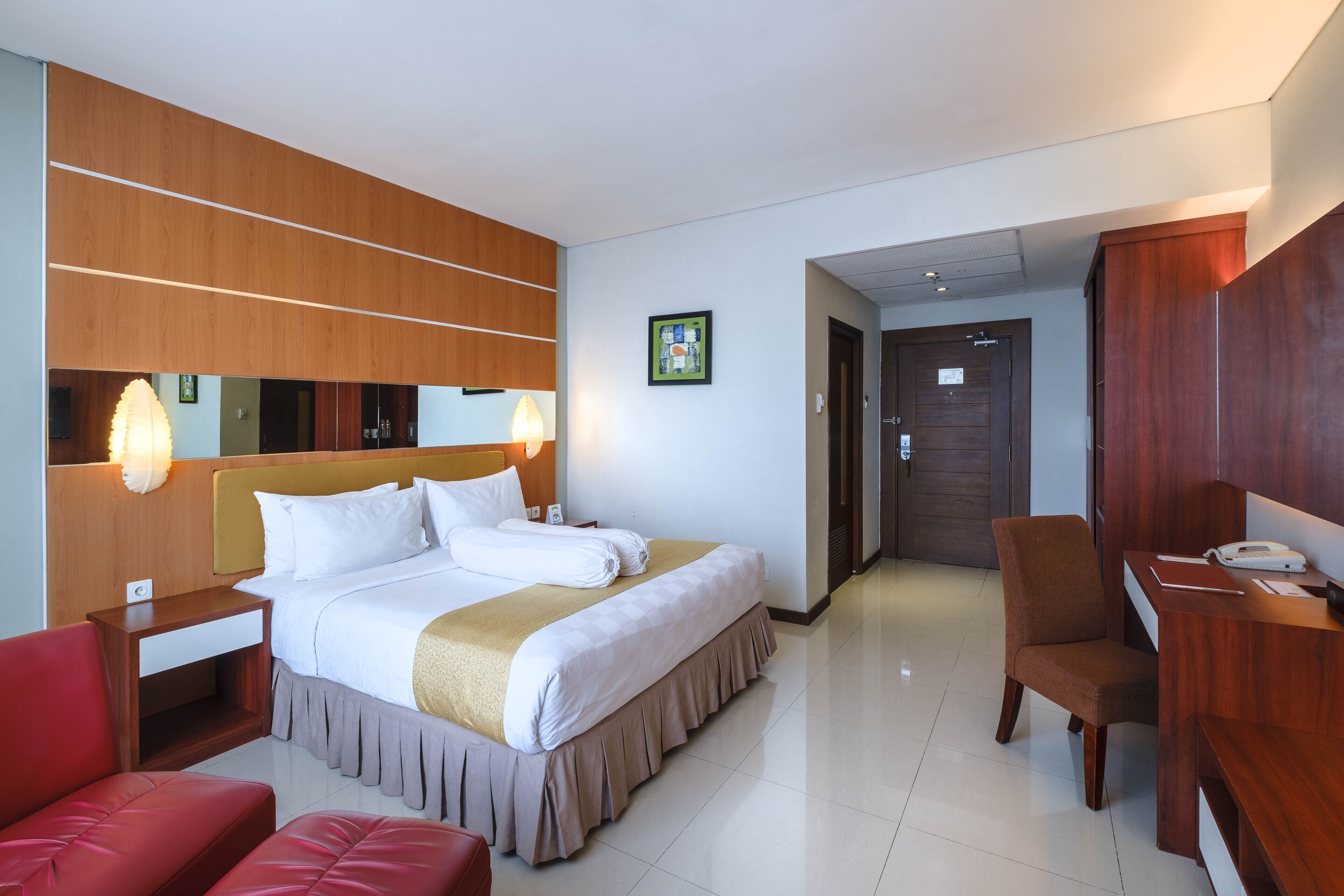 Une chambre d’hôtel avec un grand lit, un bureau, une chaise et un miroir.