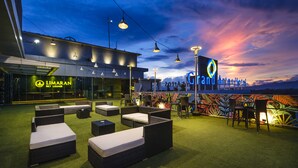 A rooftop lounge area with outdoor seating and a view of the Grand Artes Hotel. - Grand Artos Hotel & Convention (Magelang)