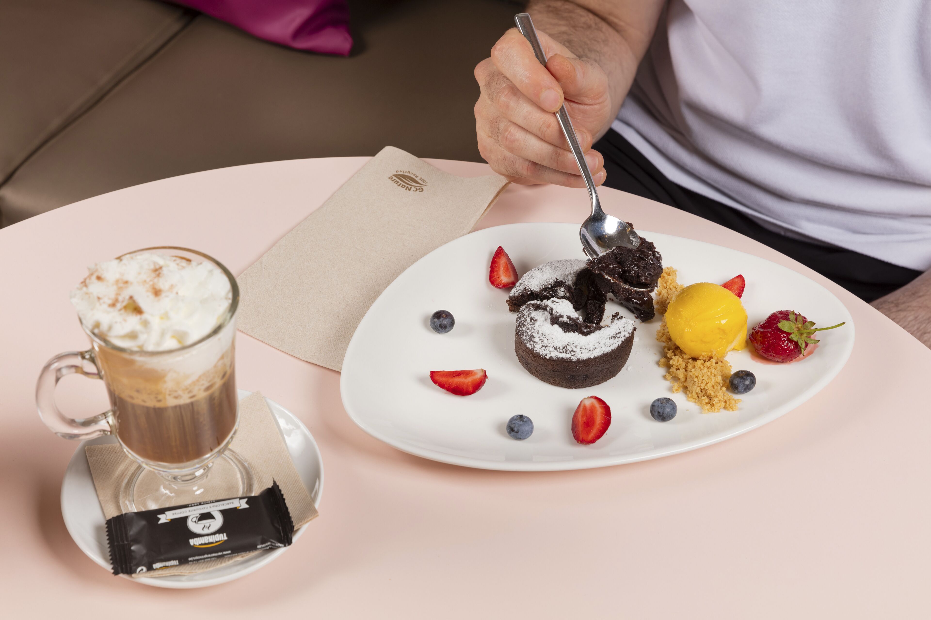 Ein Dessertteller mit Schokoladenkuchen, Erdbeeren, Blaubeeren und einer gelben Frucht auf weißem Geschirr.