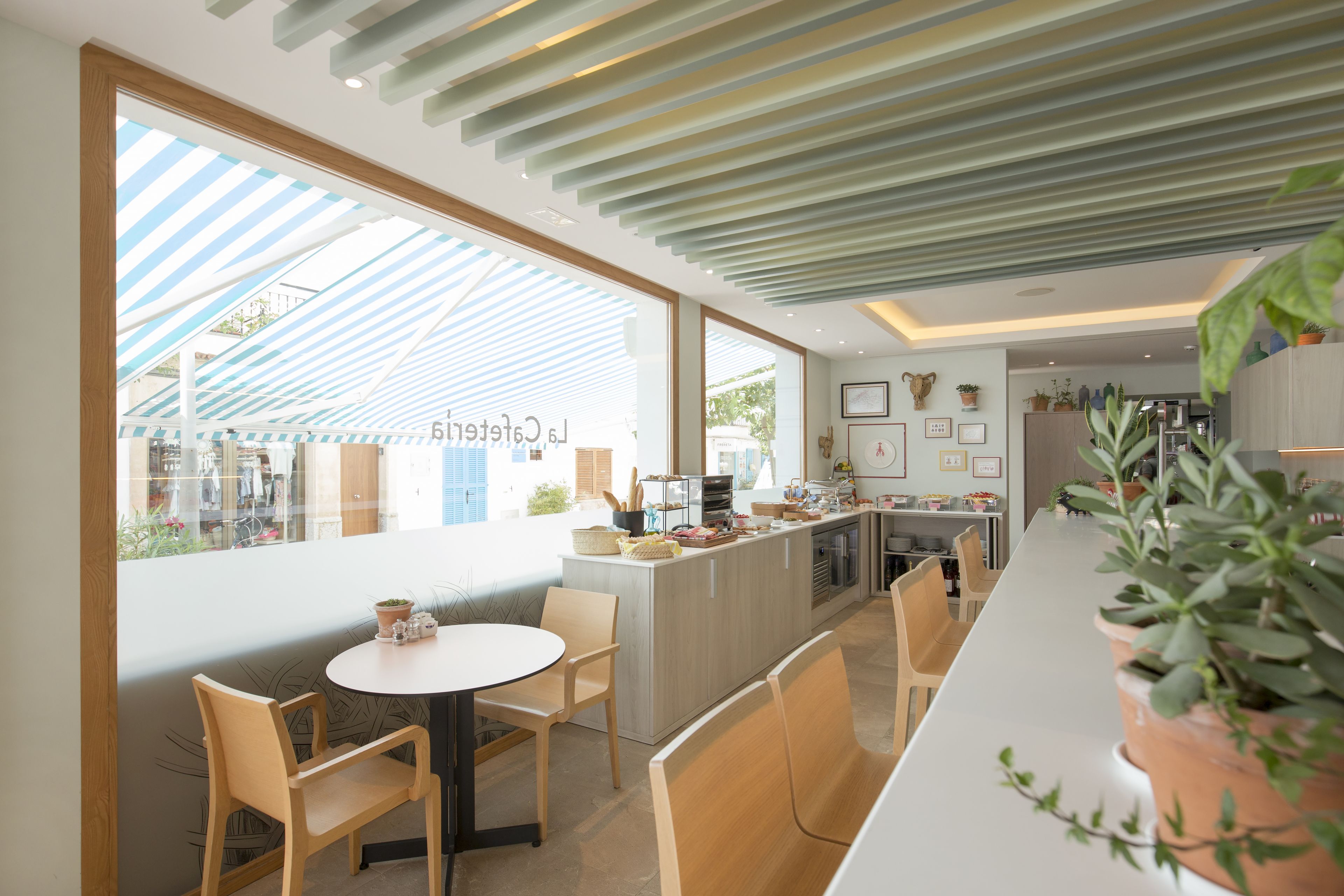 A modern restaurant with a long counter, wooden chairs, and large windows.