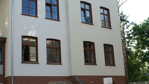 Un immeuble à plusieurs étages, doté d’une façade blanche et de bordures marron, avec de nombreuses fenêtres et une base en pierre.