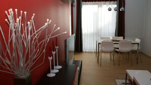 Un espace de salle à manger moderne, avec un mur d’accent rouge, une table à manger avec des chaises et une sculpture en verre décorative.