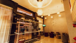 En hotellobby med modern design, med en receptionsdisk, en sittgrupp och dekorativ belysning.
