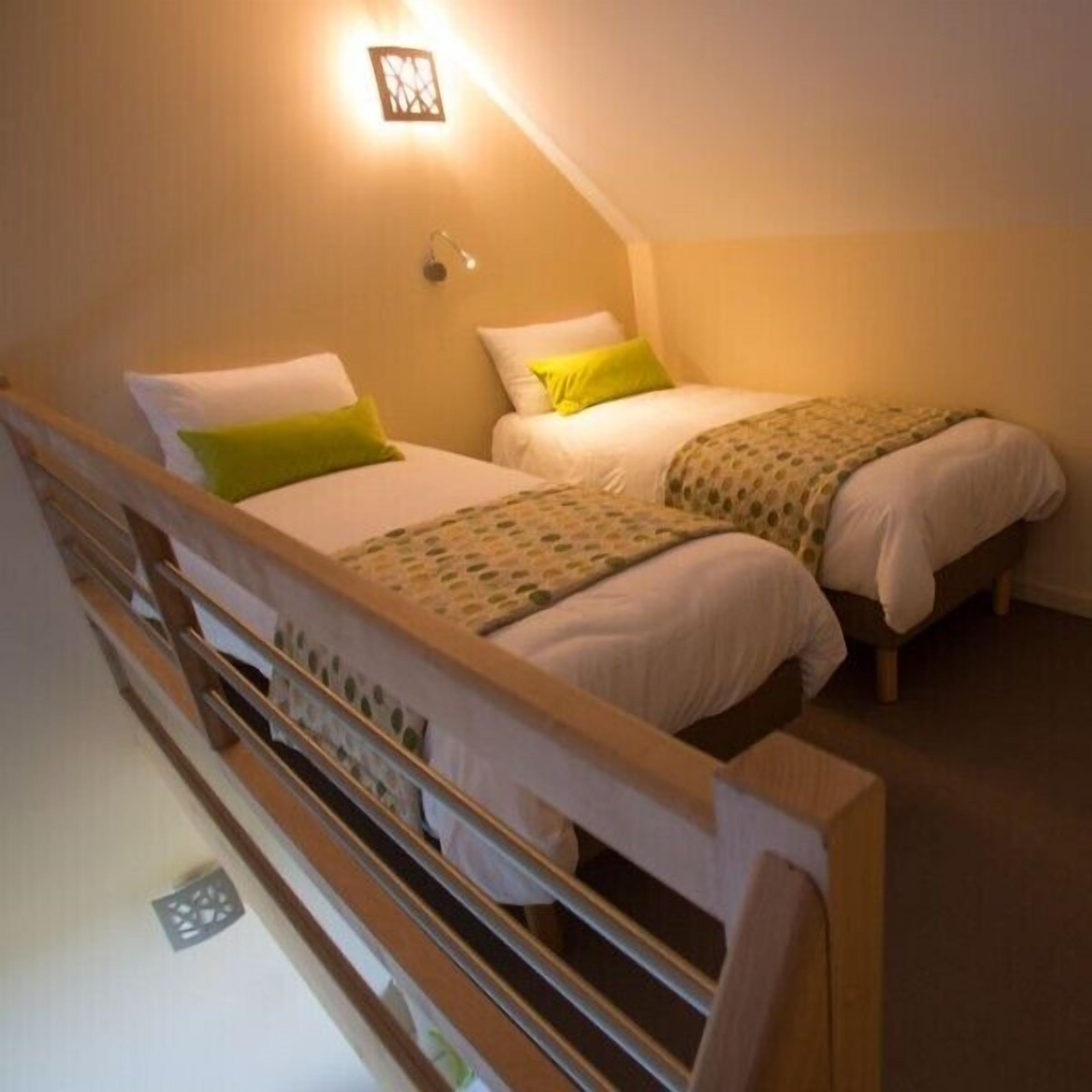 A bedroom with two single beds, each with a pillow and a blanket.