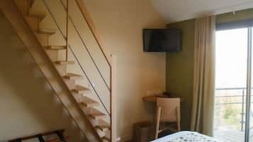 Un dormitorio con una cama, un escritorio, una silla, un televisor y una escalera.