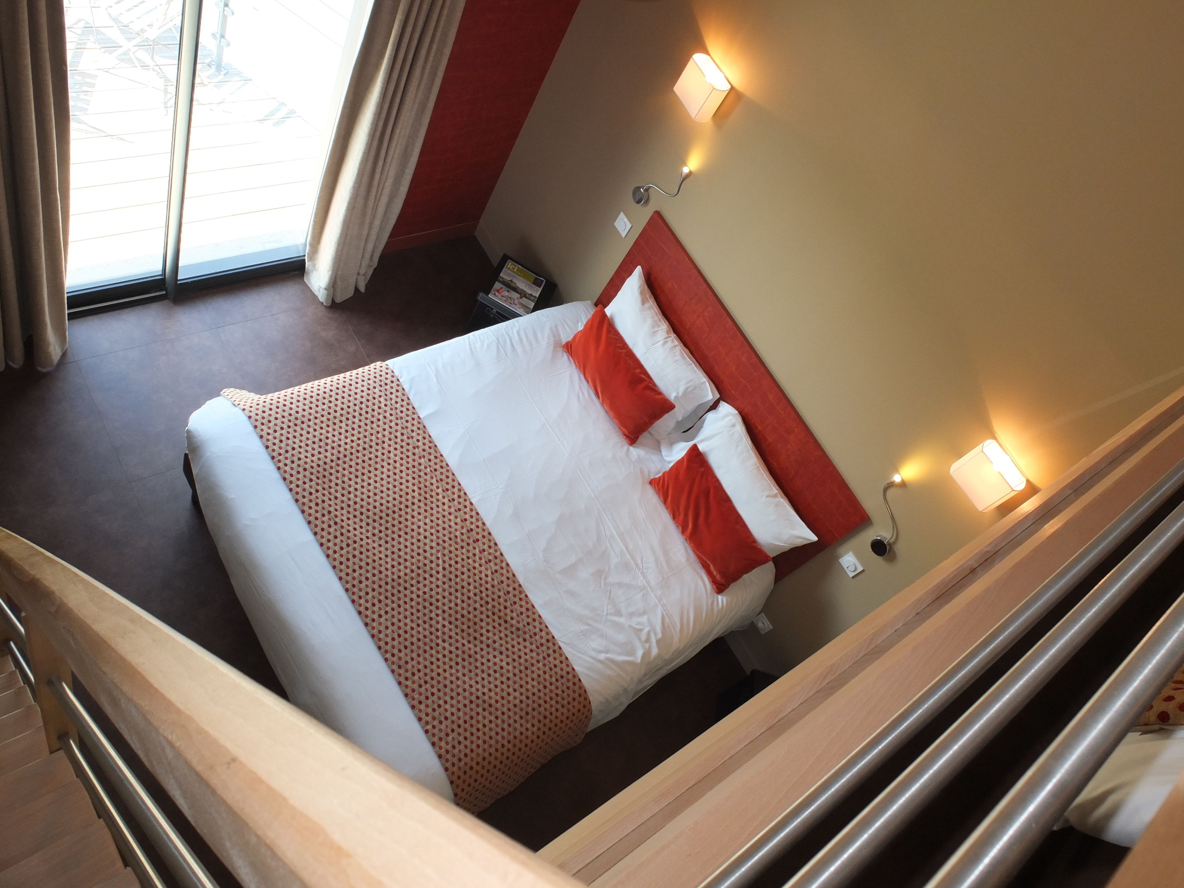A hotel room with a bed, a nightstand, a lamp, and a window with curtains.