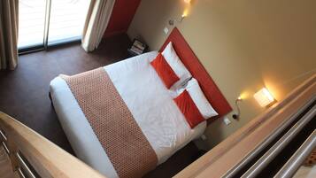 A hotel room with a bed, a nightstand, a lamp, and a window with curtains.