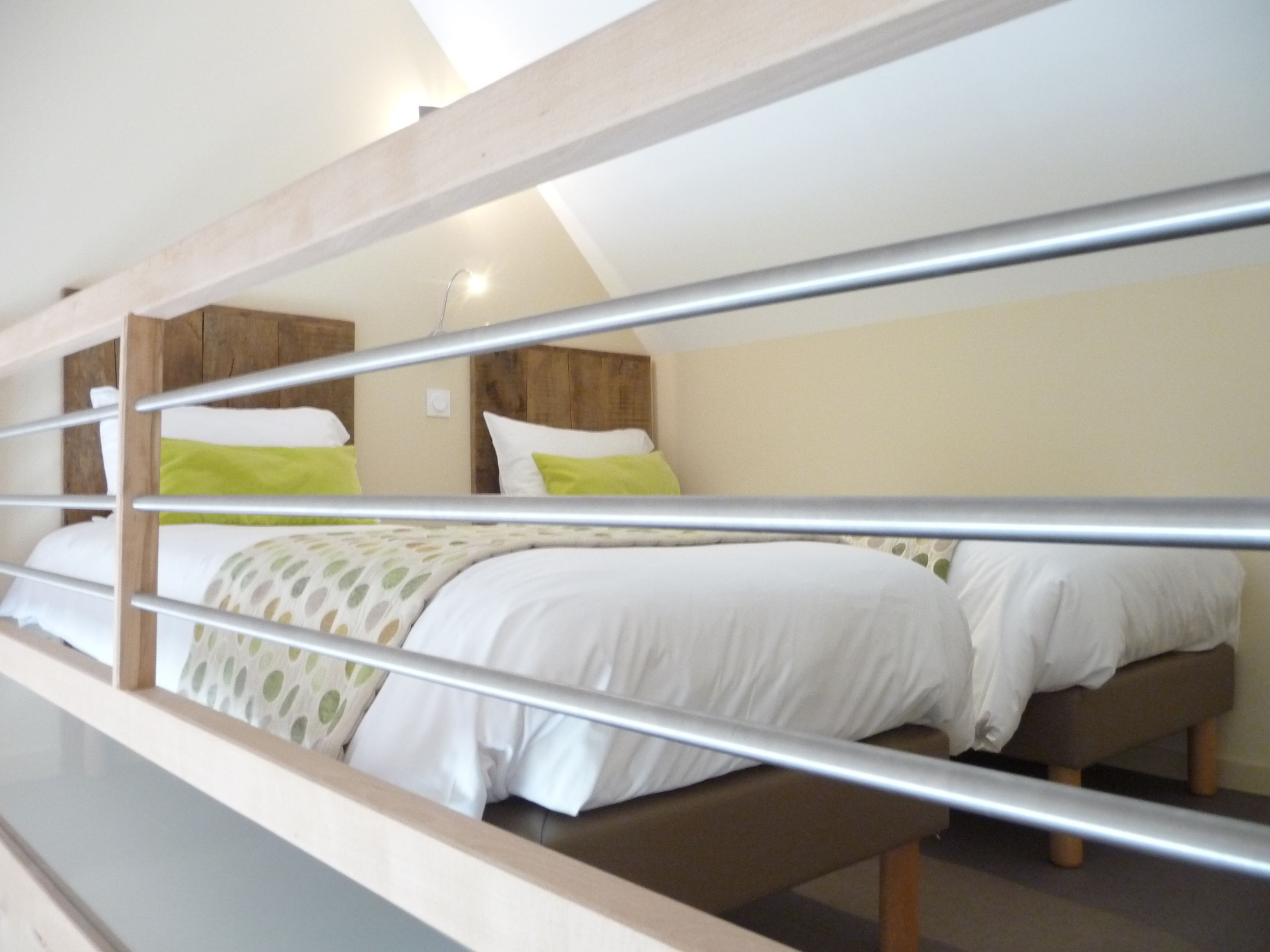 A bunk bed room with a wooden headboard, a bench, and a light-colored wall.