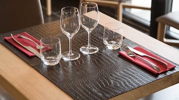 A table set with four wine glasses and cutlery on a textured tablecloth.