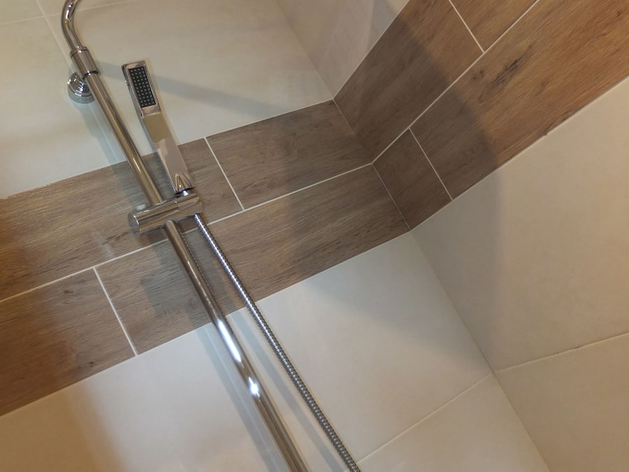 Une douche équipée d’un pommeau de douche à main et d’un panneau de commande fixé au mur.