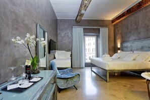 A hotel room with a bed, a chair, a desk with wine glasses, and a view of the outside. - Mama's Home Rome (Rome)