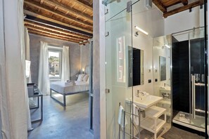 A modern bedroom with a bed, bedside table, and a view of the outside.