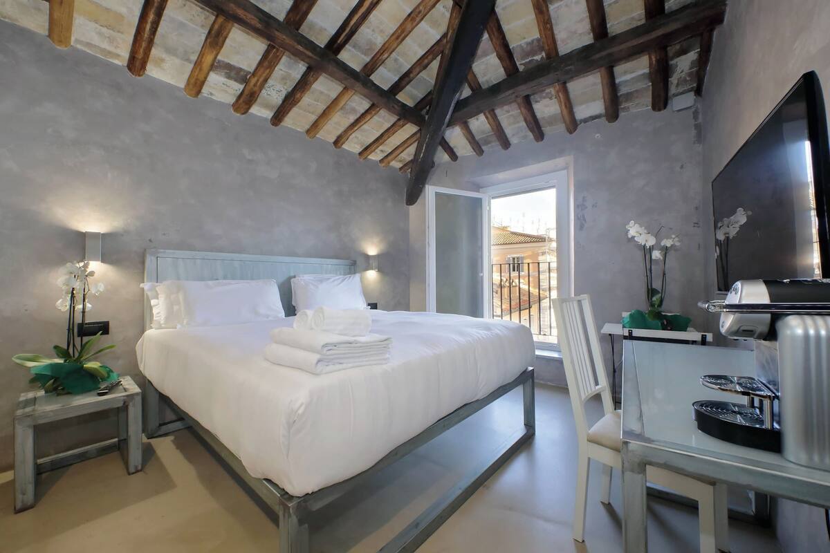 A bedroom with a bed, bedside table, and a desk with a chair.