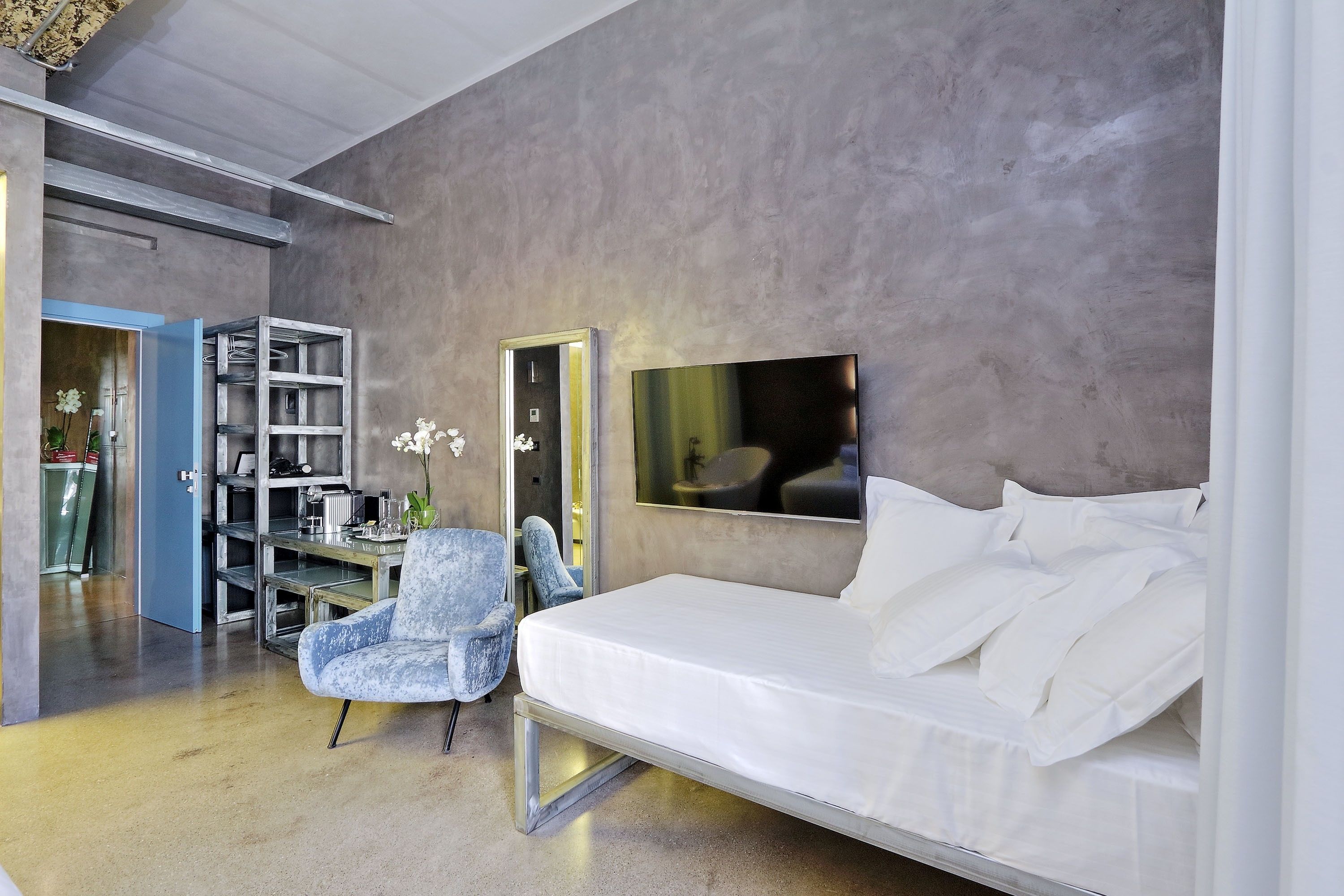 A modern bedroom with a bed, a chair, a desk, and a wardrobe.