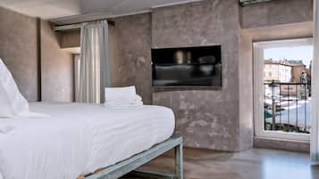 A bedroom with a bed, a TV mounted on the wall, and a view of the outside balcony.