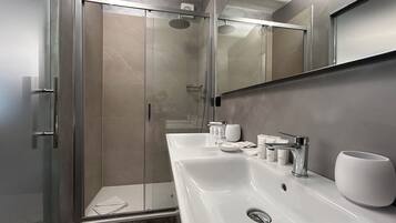 A modern bathroom with a glass-enclosed shower, a double sink with a mirror above, and a marble floor.