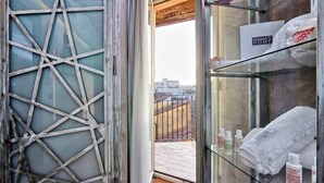 Habitación de hotel con vista a la ciudad, una puerta de cristal y un estante con artículos de aseo.