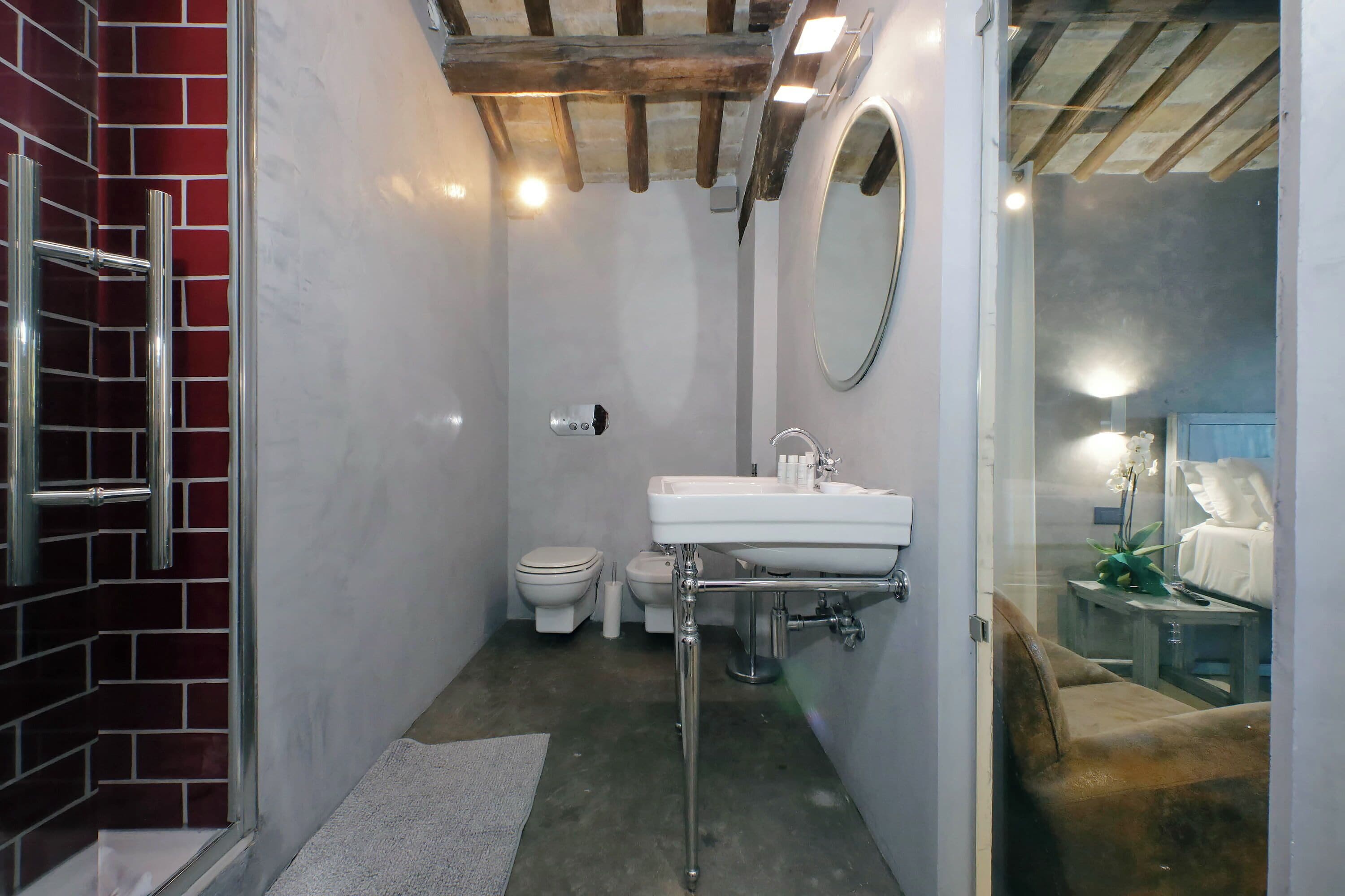 A compact bathroom with a white sink, a mirror, a toilet, and a shower area.