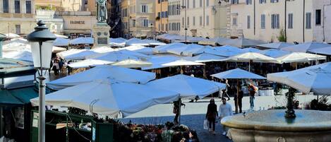 A bustling outdoor market with numerous white umbrellas and stalls selling flowers.