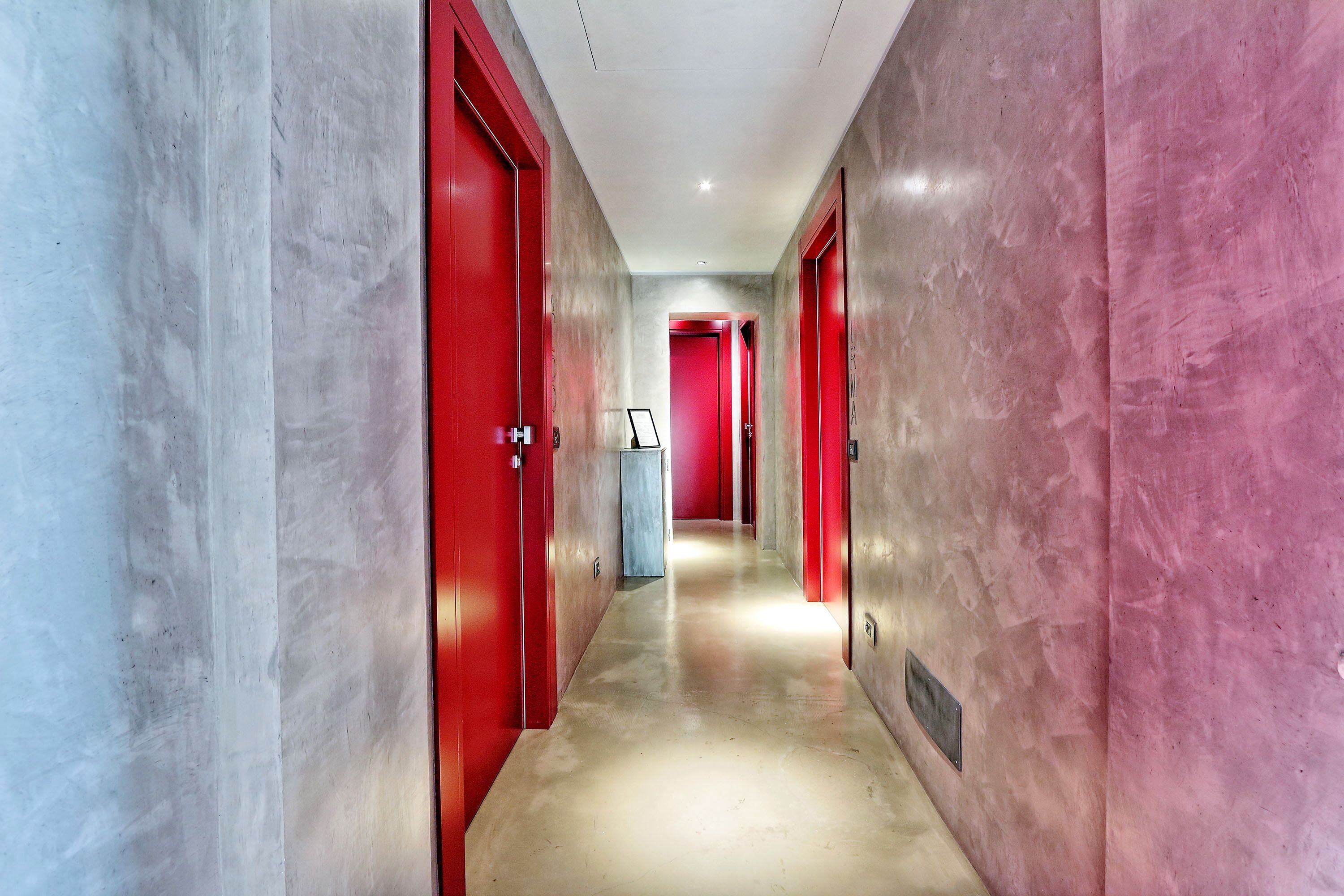 Un pasillo con puertas rojas y suelo de mármol.