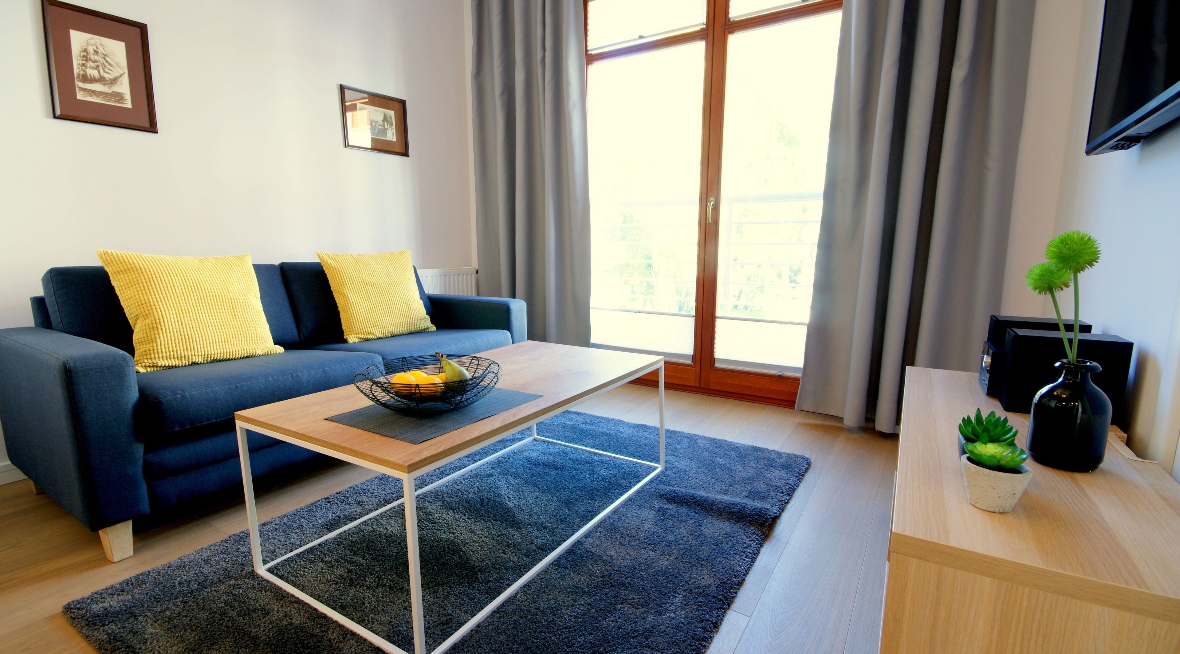 A modern living room with a sofa, coffee table, and a small plant on a side table.