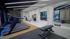 A modern gym with treadmills, weights, and exercise equipment. - IRS ROYAL APARTMENTS - IRS Neptun Park (Gdansk)