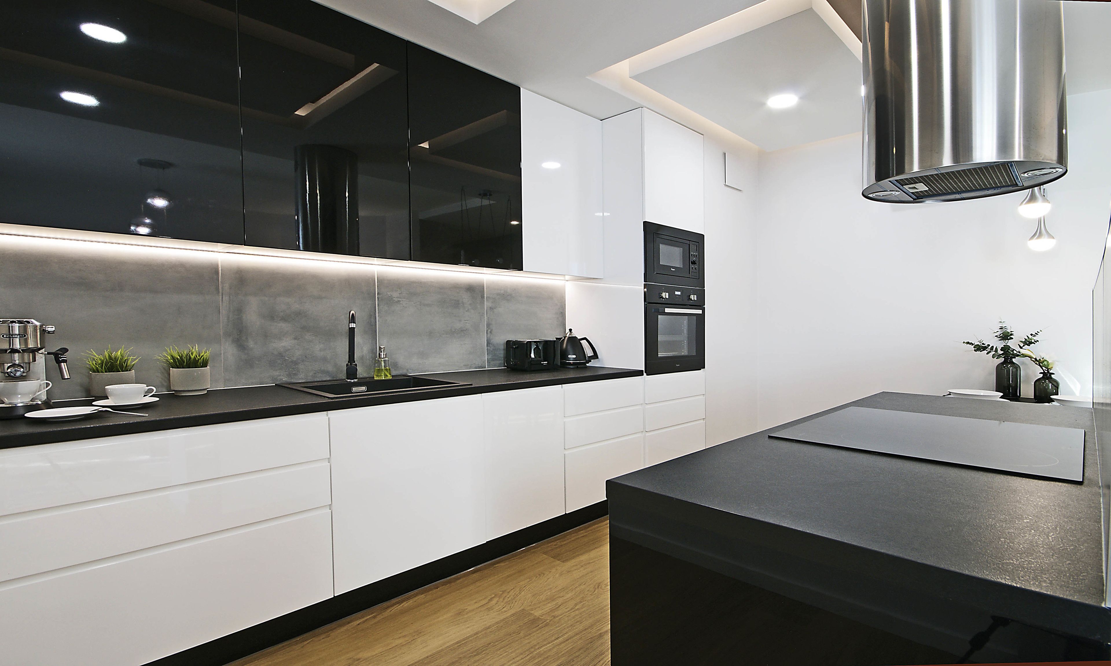 A modern kitchen with white cabinets, a black countertop, and stainless steel appliances.