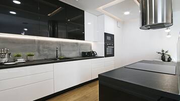 A modern kitchen with white cabinets, a black countertop, and stainless steel appliances.