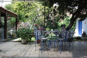 An outdoor patio with a table and chairs, surrounded by potted plants and a stone wall. - Istanbul Pansiyon (Ayvalik)