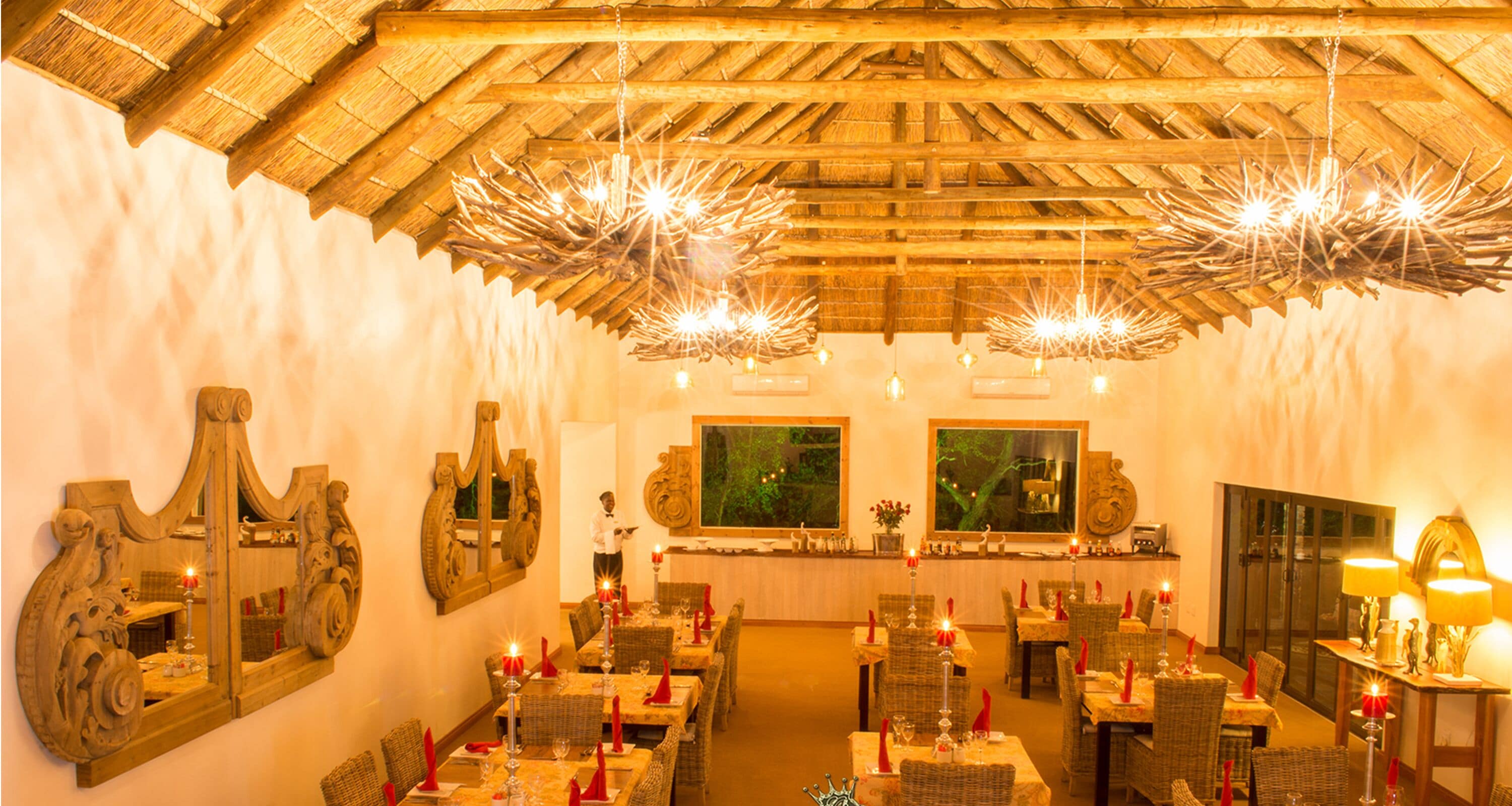 Un restaurant doté d’un plafond en bois rustique, de grands miroirs et de tables éclairées à la bougie.