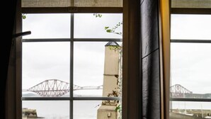 A bathroom with a large window overlooking a bridge and water.