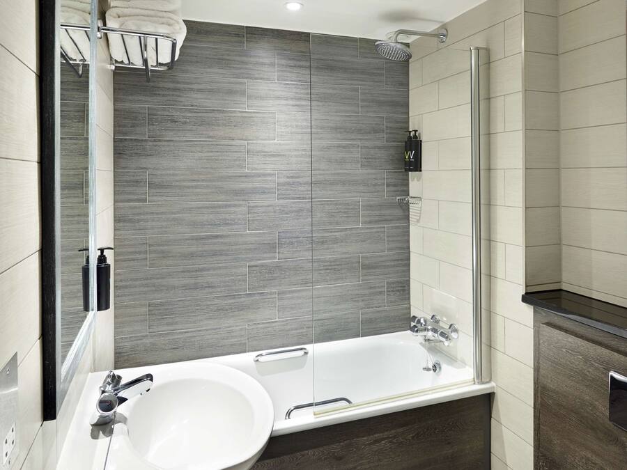 A modern bathroom with a large bathtub, a double sink, and a toilet.