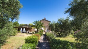A traditional stone building with a paved pathway leading to a covered outdoor seating area. - Il Vecchio Mulino Farmhouse (Radicondoli)