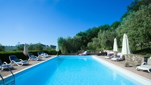 A rectangular swimming pool with clear blue water, surrounded by lounge chairs and umbrellas. - Il Vecchio Mulino Farmhouse (Radicondoli)
