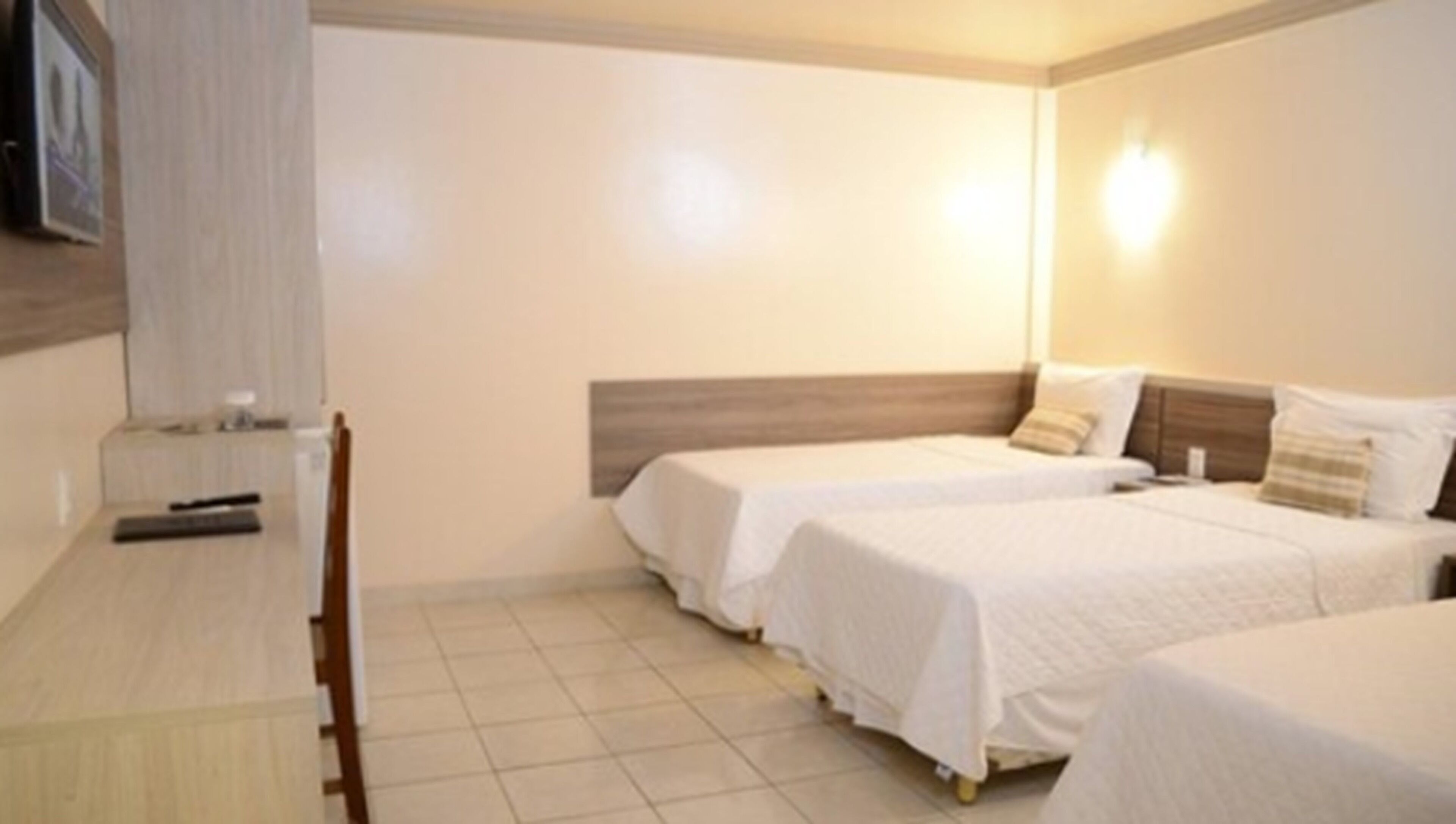 A hotel room with two single beds, a wooden desk, and a chair.