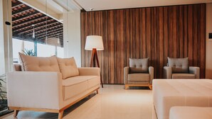 Una sala de estar moderna con un sofá, dos sillones, una lámpara y una pared decorativa de madera.