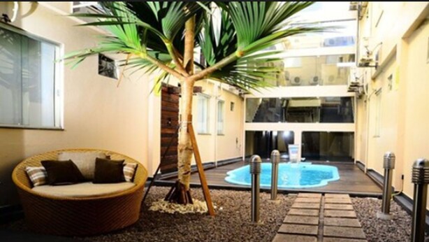 Un espacio interior acogedor con un sofá de mimbre, una pequeña palmera y un jacuzzi.