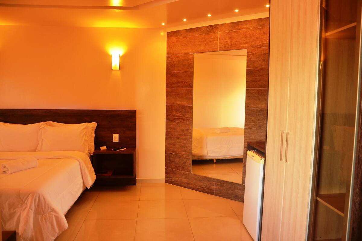 Une chambre d’hôtel moderne avec un grand lit, une table de chevet et une armoire.