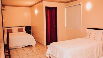 A hotel room with two beds, a wooden door, and a window.