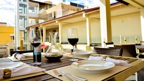 Mesa para dos con copas de vino y una botella, con vistas a un edificio con balcones.