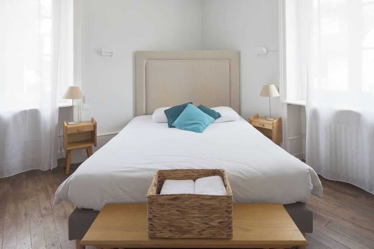 A neatly made bed with a headboard, a bedside table with a lamp, and a wooden nightstand.