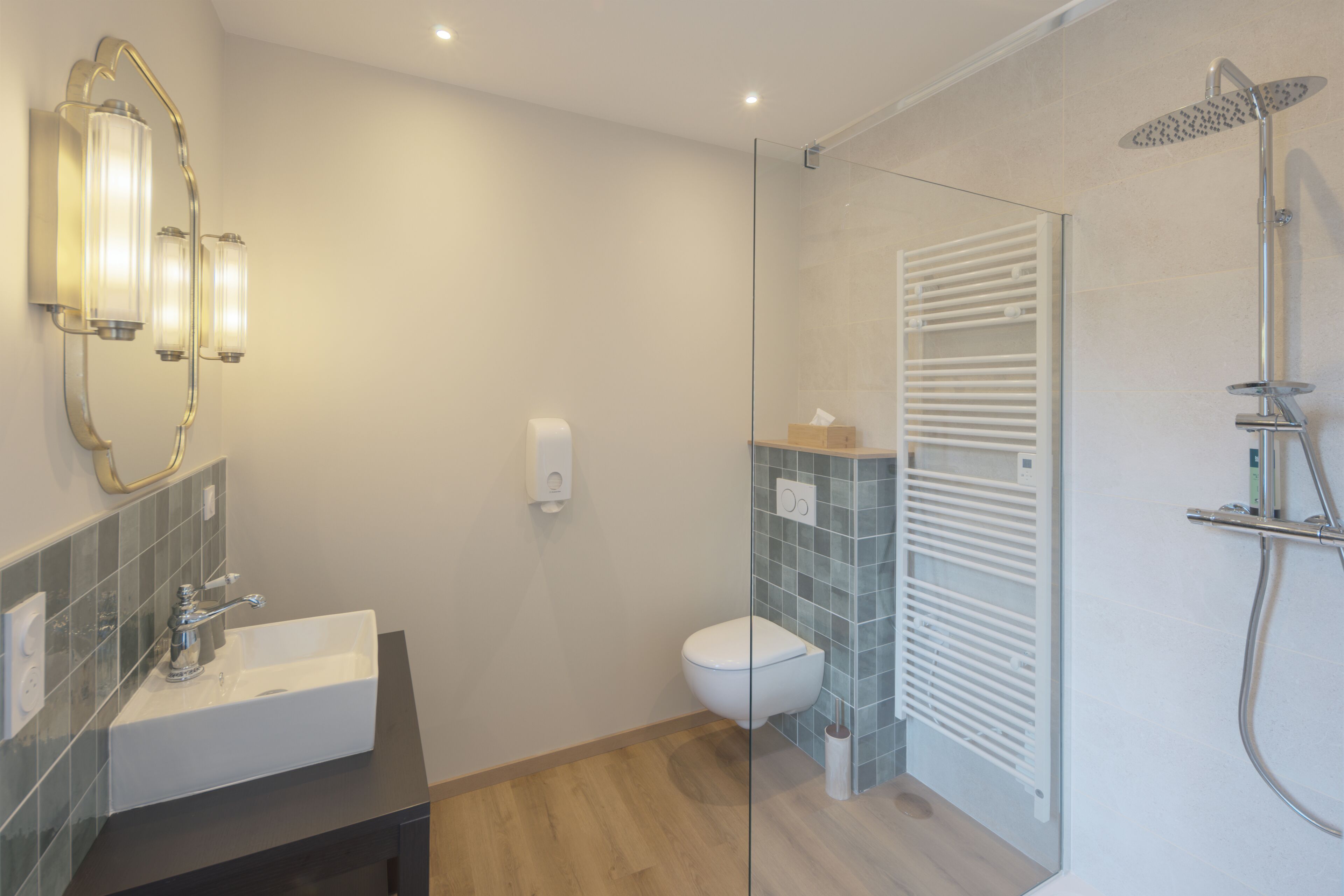 Een moderne badkamer met een wastafel, toilet, douchecabine van glas en een handdoekhouder.
